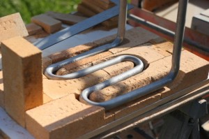 We carved the stainless steel hot water coil into the back of the firebox's replaceable liner. If we did it again, I think I would explore casting the whole back of the firebox around the pipes. stainless steel hot water pipes carved into replaceable firebox liner