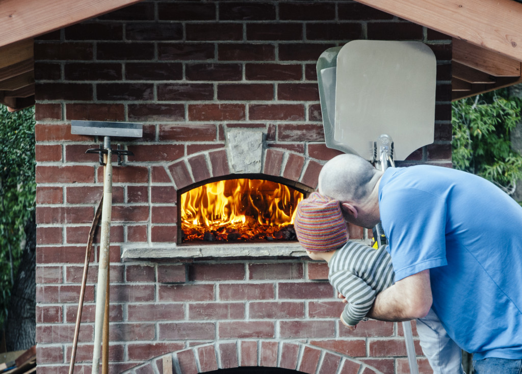 Father and child looking at brick wood-fired oven